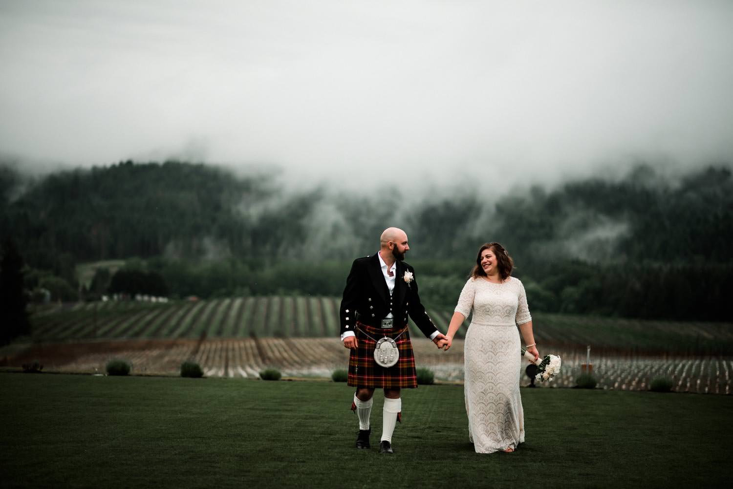 Bride and groom walking in the foggy vineyard after their wedding ceremony at Abbey Road Farm Wedding venue in Carlton Oregon.