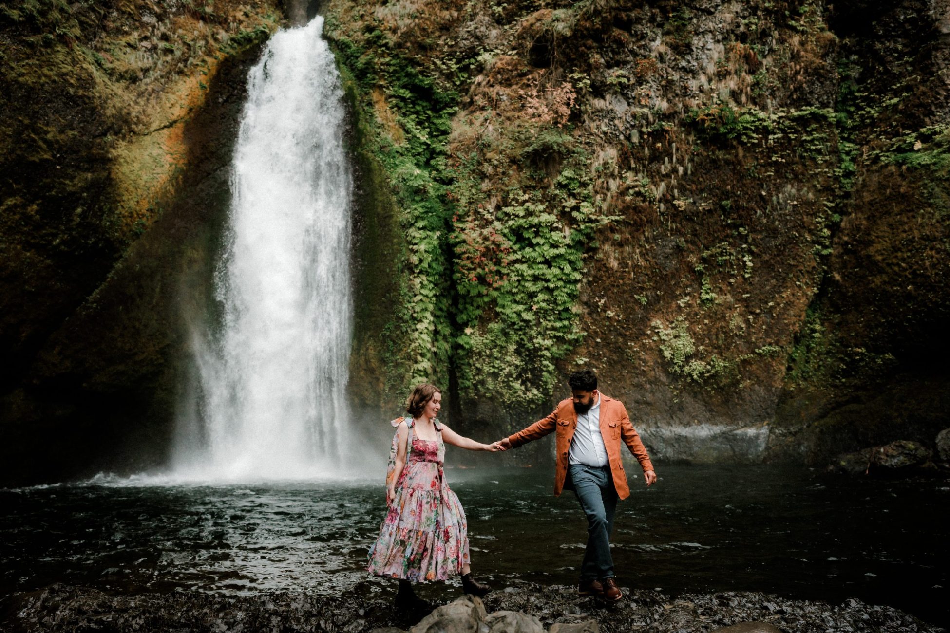 Wahclella Falls engagement photo with colorful and happy couple with a dramatic and moody waterfall backdrop in Oregon