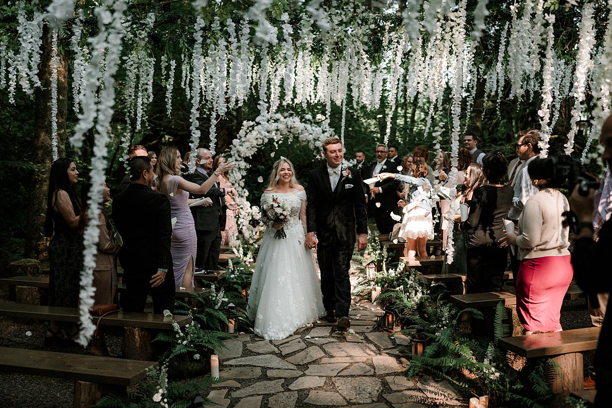 Married couple exiting ceremony during Twilight themed wedding at Fern Acres in Forks Washington by Portland Oregon photographer Dionne Kraus
